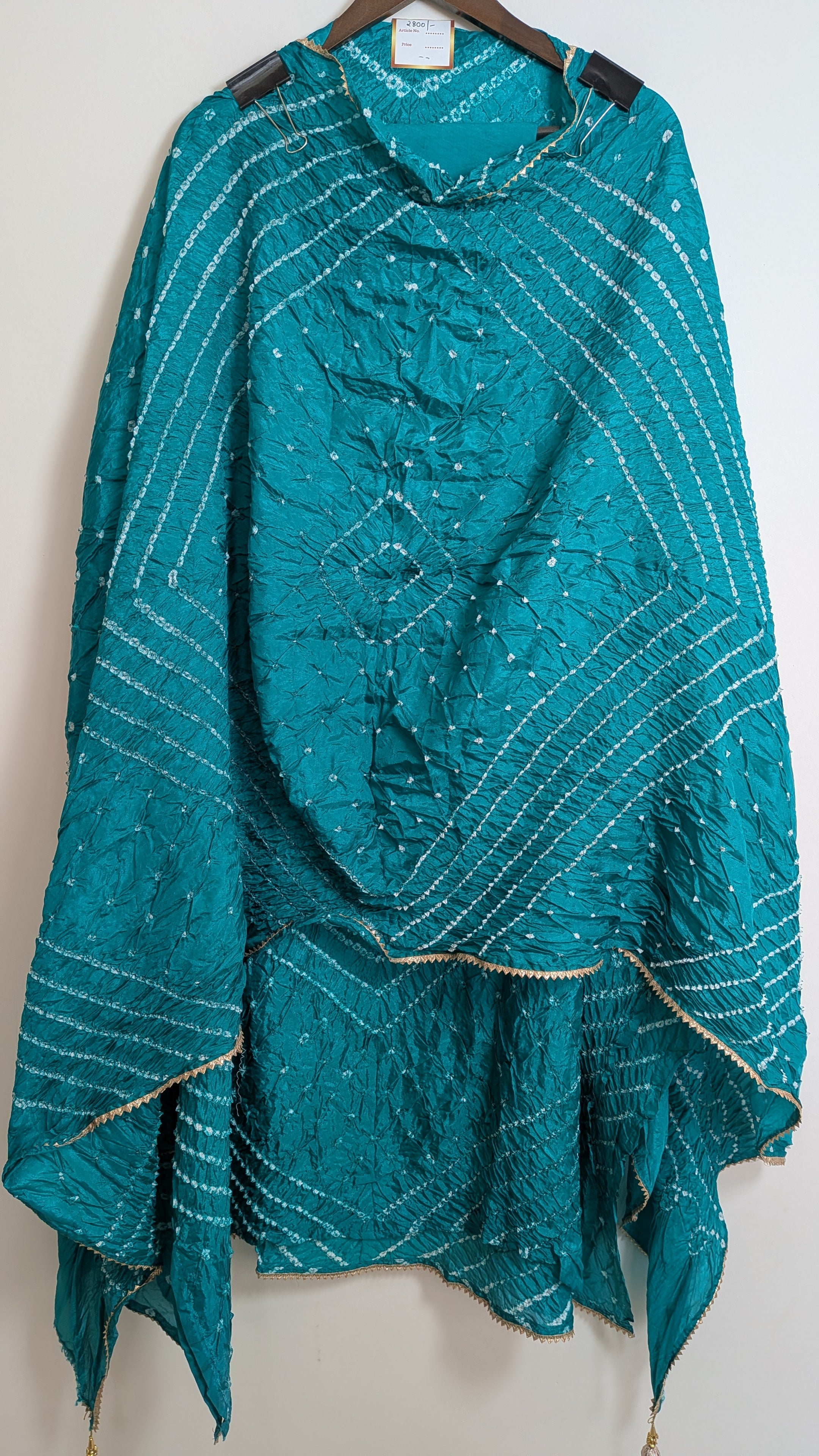 Teal patterned fabric on a hanger against a white background