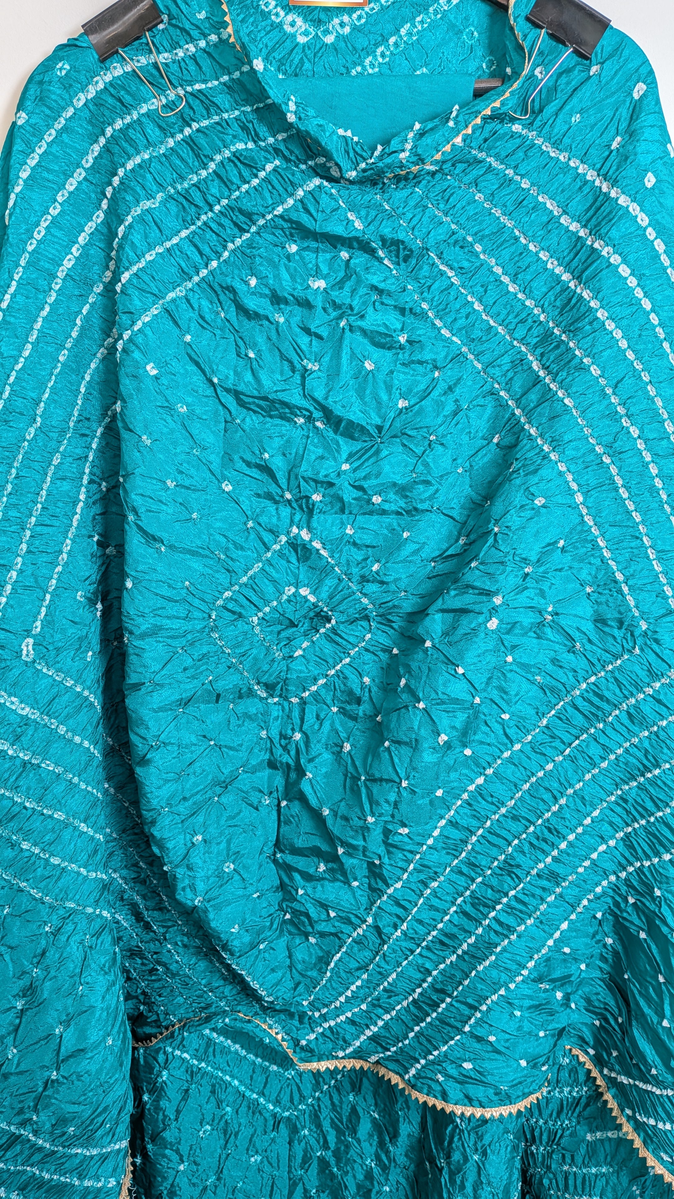 Close-up of a teal fabric with white embroidery on a white background