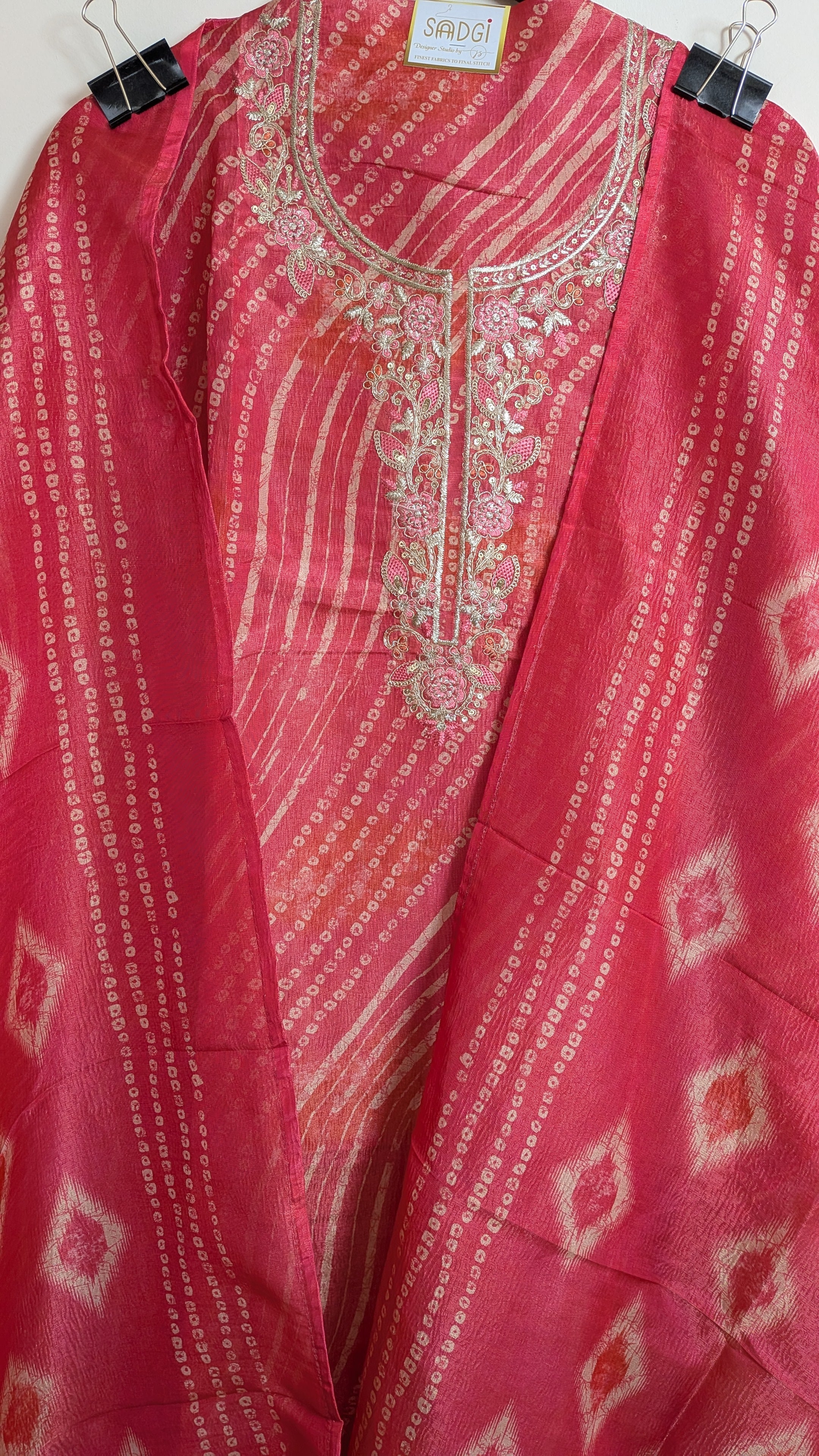 Red embroidered traditional outfit with a patterned fabric on a plain background