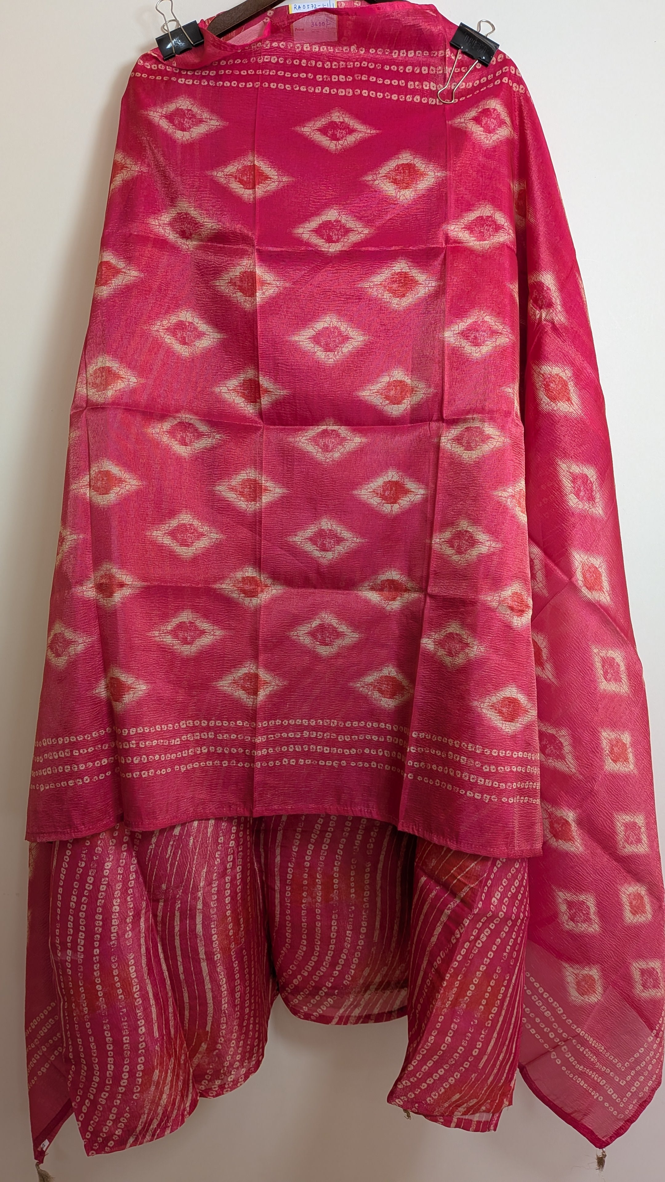 Pink fabric with geometric patterns hanging on a white wall