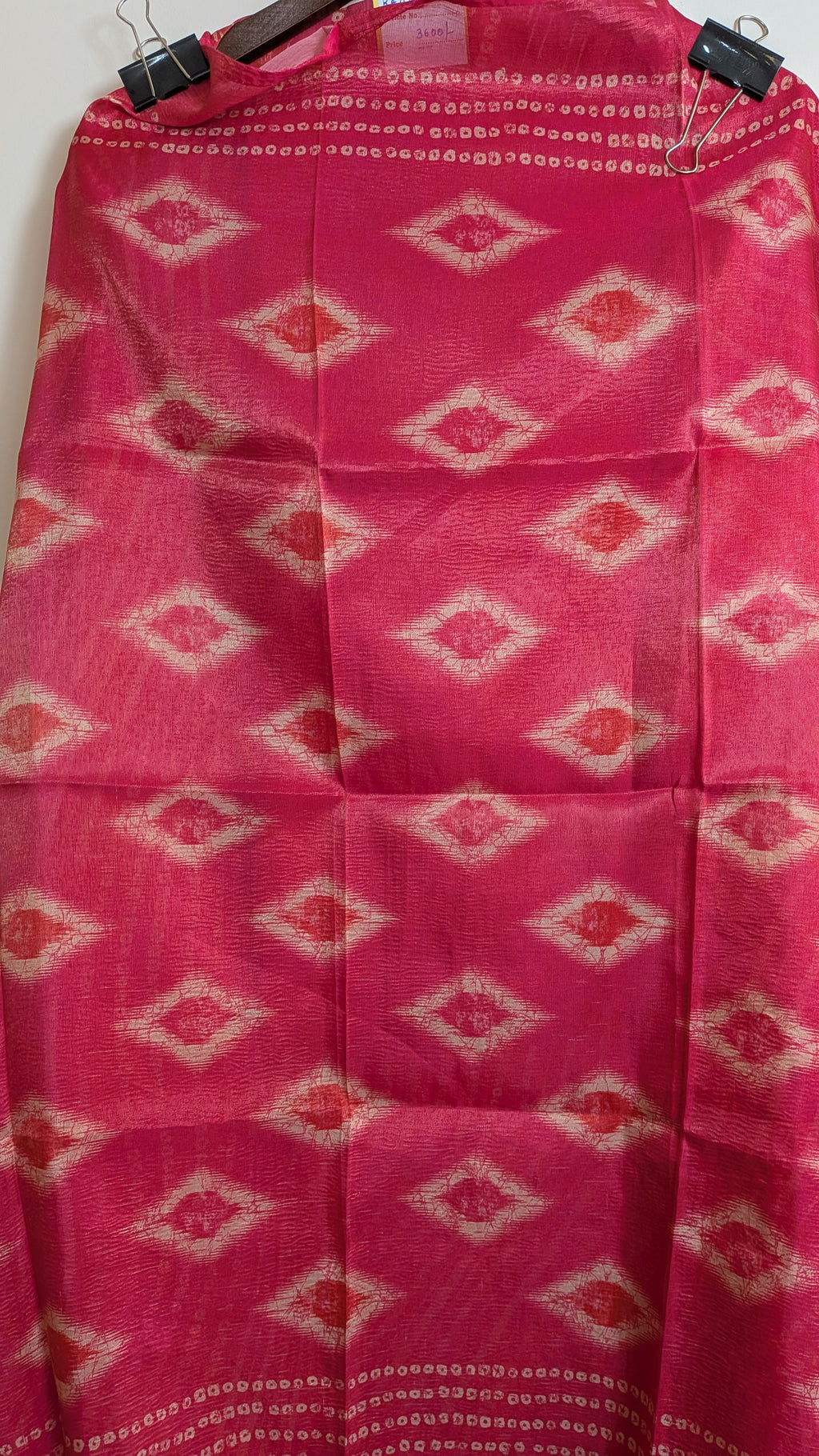 Pink fabric with diamond pattern hanging on a wooden rod