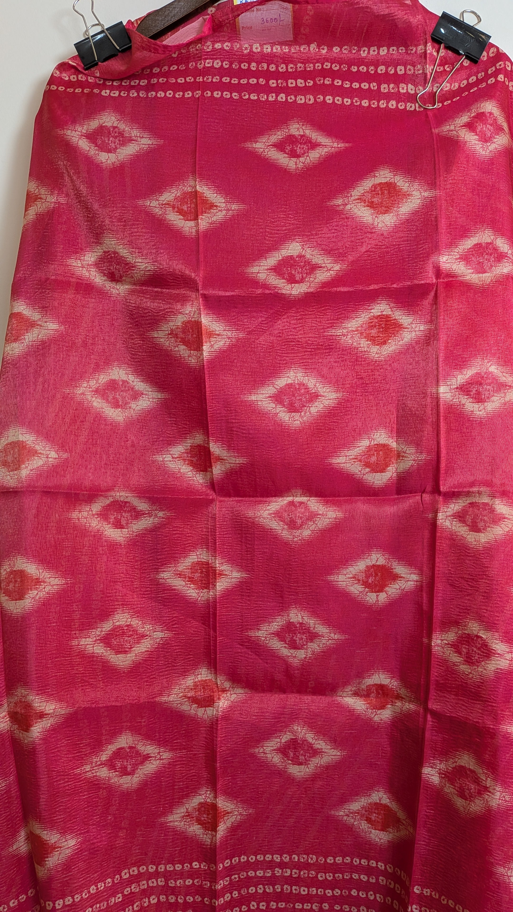 Pink fabric with diamond pattern hanging on a wooden rod