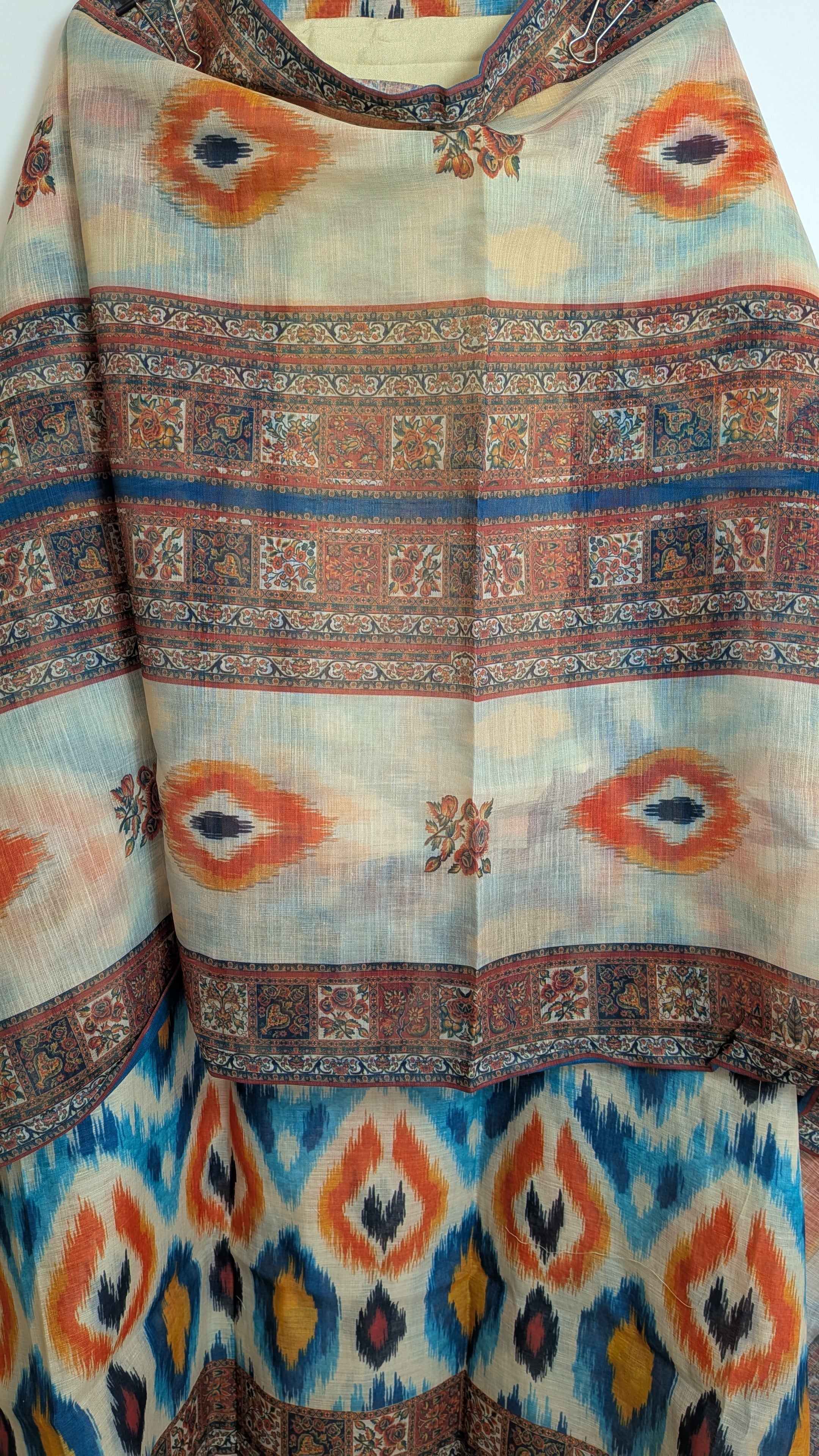 Patterned fabric with tribal design in orange, blue, and brown on a white background